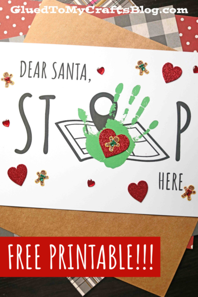 A santa stop here card with "Dear Santa, STOP here" written on it, featuring a green handprint forming the letter O, decorated with red glitter hearts and gingerbread stickers. Text at the bottom reads FREE PRINTABLE!!!.