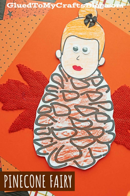 Finished paper pine cone fairy craft with colorful wings and a smiling face, ideal for fall decor.