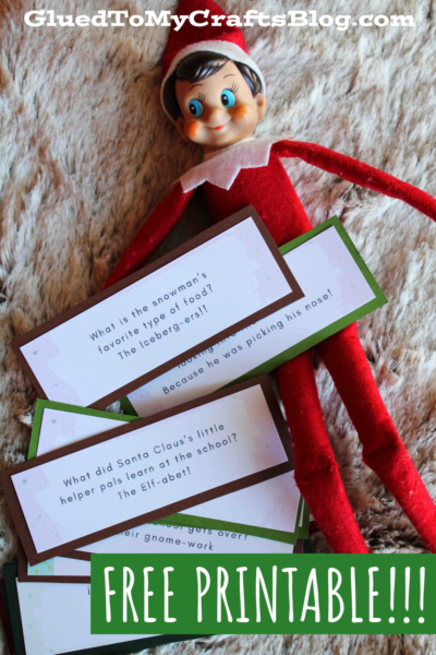 A red Elf on the Shelf doll lies on a textured surface next to several printable joke cards. The cards feature Christmas jokes for kids, and a large text overlay at the bottom reads, FREE PRINTABLE!!!.