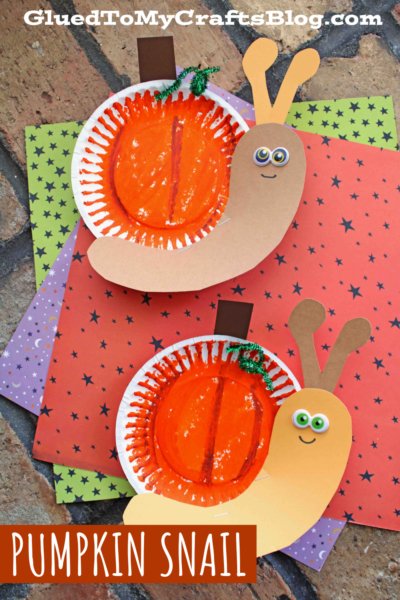 Two pumpkin snail crafts made from paper plates painted orange, with brown and tan paper bodies, green pipe cleaner stems, and googly eyes, set on star-patterned colored paper.