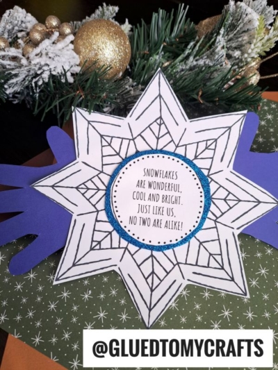 A handmade handprint snowflake craft with a blue border and the words, Snowflakes are wonderful, cool and bright. Just like us, no two are alike!, set on festive green and orange paper with snowflake patterns.