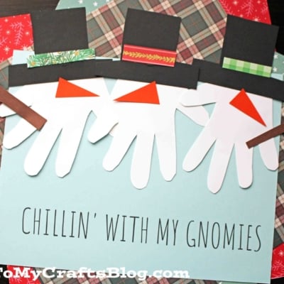 Three handprint snowman gnomes are crafted from cutout handprints and decorated with hats, noses, and arms. A sign below reads CHILLIN WITH MY GNOMIES on a blue background with patterned paper.