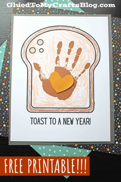A fun craft project featuring a toast to a new year card shaped like toast, with a handprint and paper heart in the center. “TOAST TO A NEW YEAR!” and “FREE PRINTABLE!!!” are featured, set on colorful star-patterned paper.