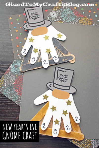 Two handmade Popsicle Stick New Year's Eve Gnome crafts feature white handprint beards, glittery gold stars, hats reading Happy New Year, and 2024 on the fingers, displayed on festive starburst paper.