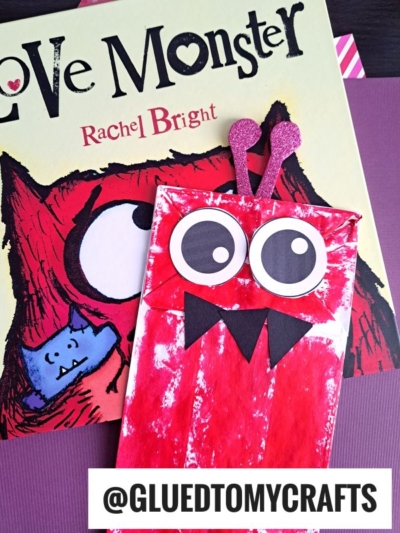 A children’s book titled Love Monster by Rachel Bright is shown with a paper bag love monster craft featuring big googly eyes, black paper teeth, and pink glitter heart antennae. The handle @GLUEDTOMYCRAFTS is displayed.