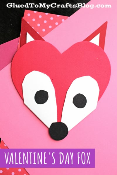 A handmade Valentines Day fox craft made from red, white, and black paper arranged in the shape of a heart, perfect for heart shaped crafts or valentine art project ideas. Set on a pink background with "Valentines Day Fox" at the bottom.