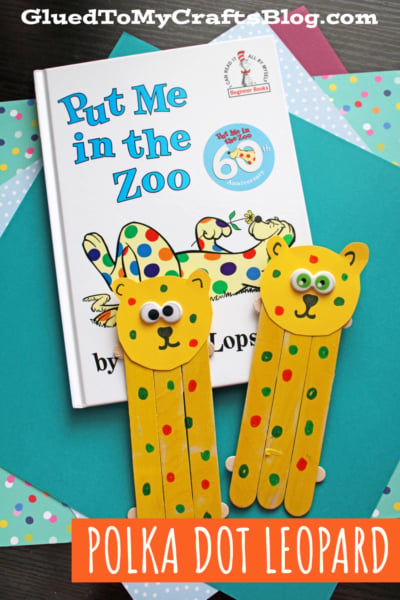 Children’s book Put Me in the Zoo is displayed with two popsicle stick leopards decorated with colorful dots and googly eyes on a polka dot background. Text reads: “Polka Dot Leopard”—a fun Put Me in the Zoo craft idea!.