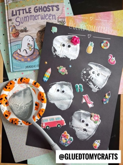 Childrens craft scene: white ghost faces with googly eyes on black paper, surrounded by colorful stickers and a Halloween plate with paint, brush, and spatula stamped crafts. A Little Ghosts Summerween book is in the corner.