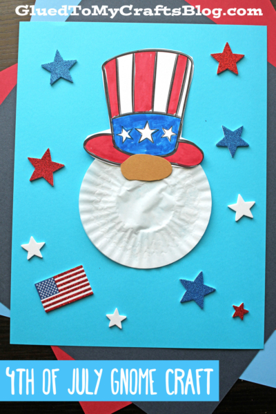 A cupcake liner gnome craft with a white beard, a hat in U.S. flag colors, and foam star decorations on blue paper. A small American flag and the text "4th of July Gnome Craft" appear at the bottom.