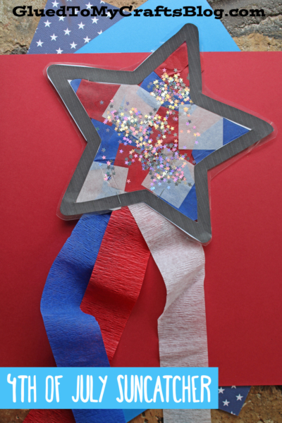 A patriotic star suncatcher decorated with red, white, and blue tissue paper, star-shaped glitter, and crepe paper streamers shines on a red background. Text reads 4th of July Suncatcher and GluedToMyCraftsBlog.com.
