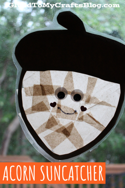 A cheerful acorn suncatcher with googly eyes, a smiling face, and heart-shaped cheeks brightens the window. Its dark brown top contrasts with the semi-transparent light brown body. Text reads: Acorn Suncatcher.