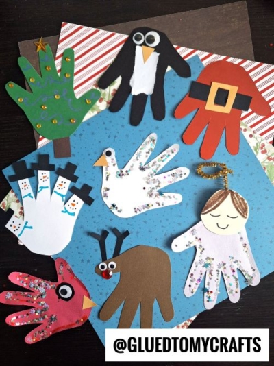 Assorted handprint crafts on patterned paper, including a Christmas tree, penguin, Santa, birds, reindeer, angel, and chicken—perfect as christmas keepsakes—decorated with googly eyes, glitter, sequins, and drawn features. @GLUEDTOMYCRAFTS watermark at bottom.