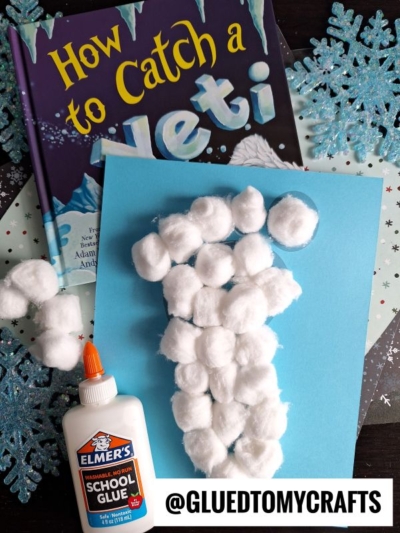 A children’s book titled How to Catch a Yeti, a sheet of blue paper with a yeti footprint shape made of cotton balls, Elmers glue, snowflake decorations, and the text @GLUEDTOMYCRAFTS.