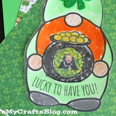 A St. Patrick’s Day leprechaun gnome craft with a green hat, glittery shamrock, and pot of gold featuring a child’s photo.