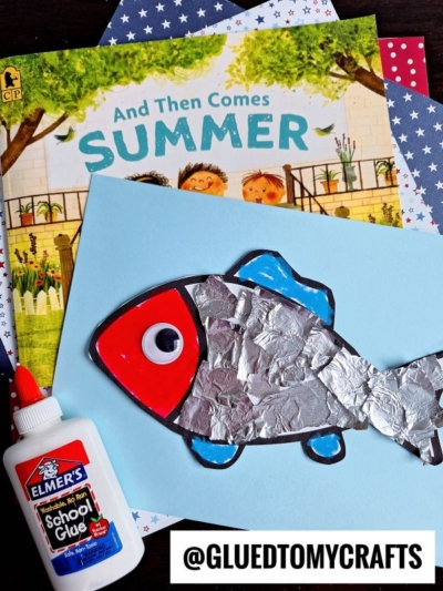A children's book titled And Then Comes Summer is shown with star-patterned paper, a glue bottle, and a torn paper fish craft made of blue paper, foil, and construction paper. An @GLUEDTOMYCRAFTS label is at the bottom.