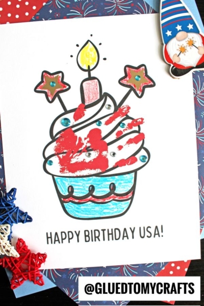 A handprint patriotic cupcake coloring sheet featuring a candle, stars, and red, white, and blue accents. Text below reads HAPPY BIRTHDAY USA! The image includes festive patriotic-themed decorations around the page.