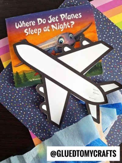 A children’s book titled “Where Do Jet Planes Sleep at Night?” is shown with a simple crepe paper airplane craft on colorful patterned paper. The @GLUEDTOMYCRAFTS handle appears at the bottom.