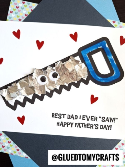 Handmade Father’s Day card featuring a foil saw with googly eyes, blue handle, red hearts, and the sweet message: Best Dad I Ever Saw! Celebrate your amazing dad with this unique keepsake. @GLUEDTOMYCRAFTS at the bottom.