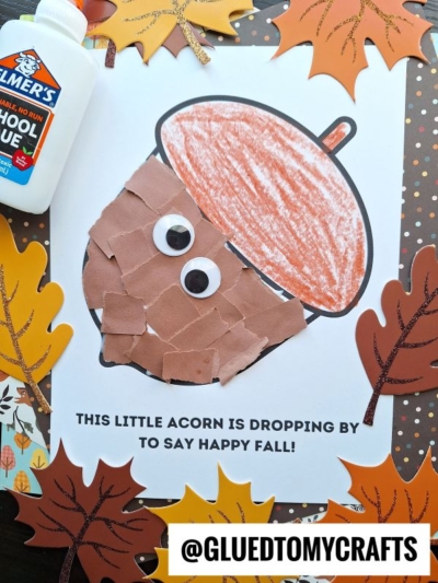 A fall-themed craft featuring a torn paper acorn made with a paper plate, googly eyes, and a colored top, surrounded by paper leaves, glue, and a cheerful greeting: “This little acorn is dropping by to say happy fall!”.