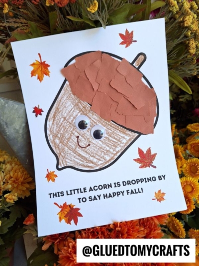 A fall-themed craft shows a torn paper acorn with googly eyes and a smiling face, surrounded by colorful leaves. The text reads, This little acorn is dropping by to say happy fall!.