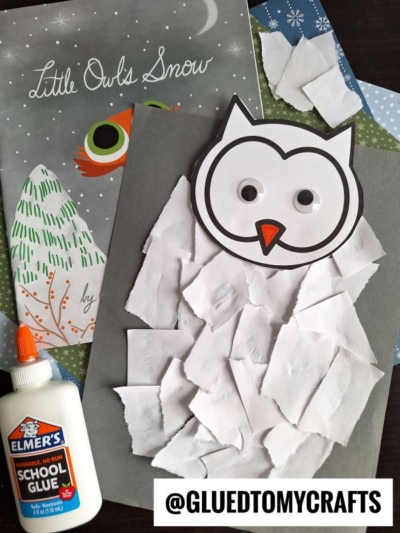 A torn paper owl with googly eyes sits on gray paper, surrounded by white paper pieces. Elmer’s school glue and the book “Little Owl’s Snow” are nearby. The handle @GLUEDTOMYCRAFTS is shown.