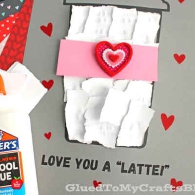 A torn paper latte craft featuring a paper coffee cup with torn white paper, a pink sleeve, and a red heart on a gray background with small hearts and the text LOVE YOU A LATTE!;
