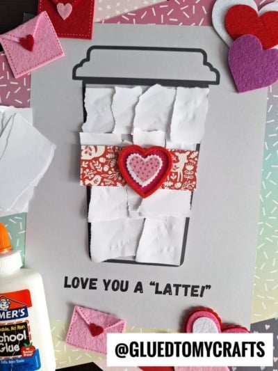 A torn paper latte craft for Valentine’s Day, featuring white paper, red patterned accents, and felt hearts on a printed cup outline. “LOVE YOU A LATTE!” adds a sweet touch to this creative coffee cup project.