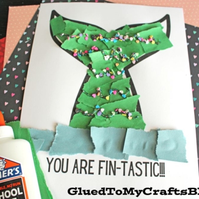 A torn paper mermaid tail craft made from green and blue paper pieces, confetti, and glue decorates a printable reading YOU ARE FIN-TASTIC!!!