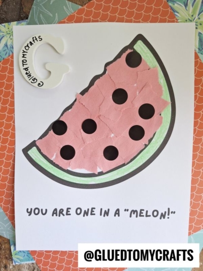 A torn paper watermelon craft featuring a vibrant slice made with pink and green paper pieces on a printed template, topped with the text YOU ARE ONE IN A MELON! and the Instagram handle @GLUETOMYCRAFTS at the bottom.