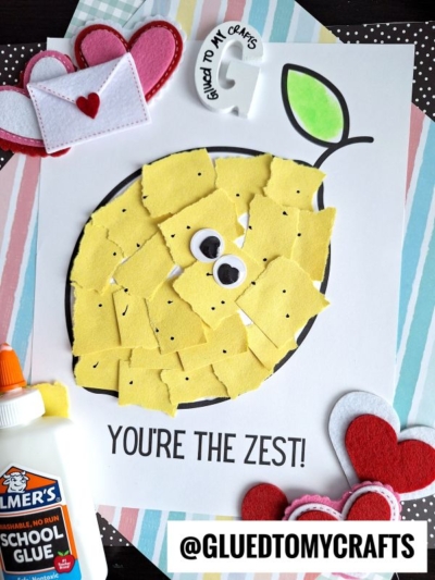 A torn paper lemon with googly eyes sits on a white sheet that says Youre the zest! It's surrounded by felt hearts, a glue bottle, an envelope, and a @GLUEDTOMYCRAFTS label.