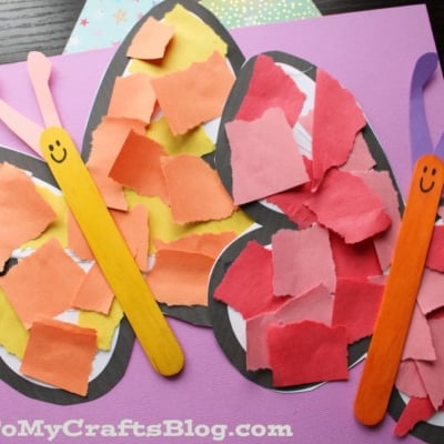 Two colorful butterfly crafts made from popsicle sticks, torn paper pieces, and black paper outlines are displayed on purple and star-patterned paper backgrounds. Each butterfly has a smiling face.