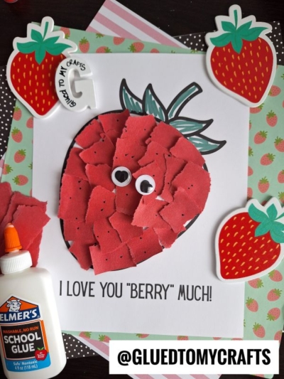 A cute kids’ craft project features a torn paper strawberry with googly eyes on a white sheet that reads, “I love you ‘berry’ much!” Surrounded by strawberry stickers, glue, and the @GLUEDTOMYCRAFTS tag.