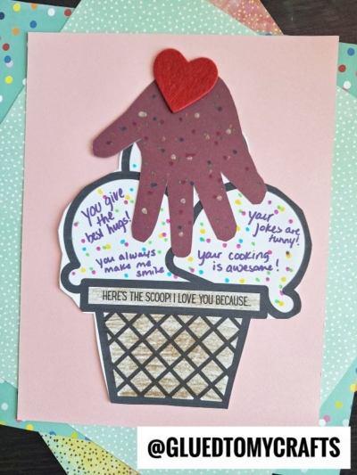 A handmade ice cream keepsake card shaped like a sundae features a brown handprint as the ice cream and a red felt heart on top. Sweet messages like You give the best hugs! are written on the scoops. @GLUEDTOMYCRAFTS is at the bottom.