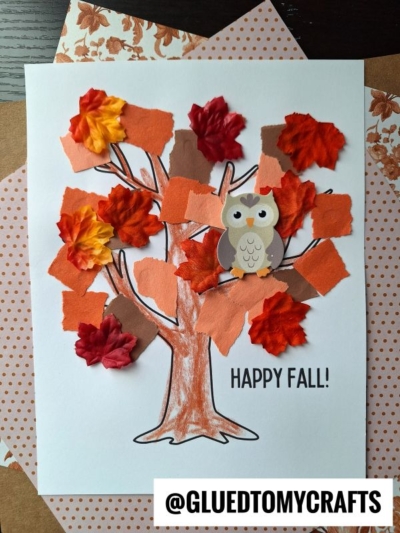 A fall-themed craft features a torn paper tree colored with brown crayon, decorated with orange paper squares, fabric autumn leaves, and a paper owl on polka dot paper. Text reads HAPPY FALL! and @GLUEDTOMYCRAFTS.