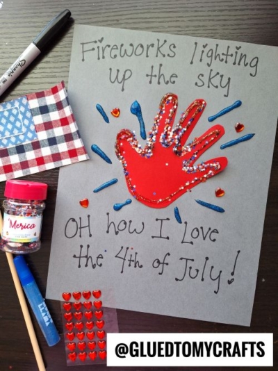 A 4th of July craft features a red handprint decorated with glitter and star stickers on gray paper, creating special 4th of July keepsakes. “Fireworks lighting up the sky, oh how I love the 4th of July!” is written amid craft supplies.