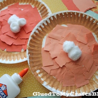Two paper plates decorated with orange and red torn paper pieces, topped with cotton balls to resemble turkeys. An Elmer’s glue bottle and patterned papers are nearby. Image source: gluedtomycraftsblog.com. Perfect for a torn paper pie craft!.