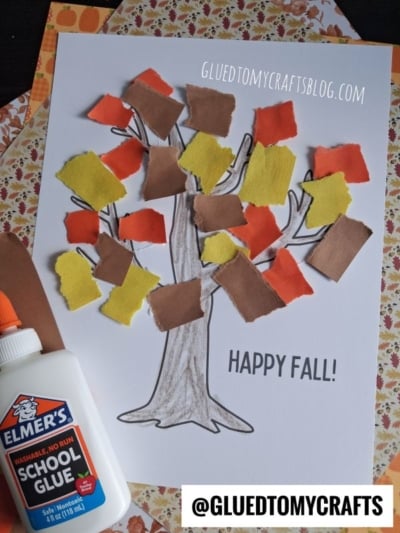 A fun torn paper tree craft using brown, yellow, orange, and red paper squares glued onto a hand-drawn tree; glue bottle visible; “Happy Fall!” and craft blog watermark shown.
