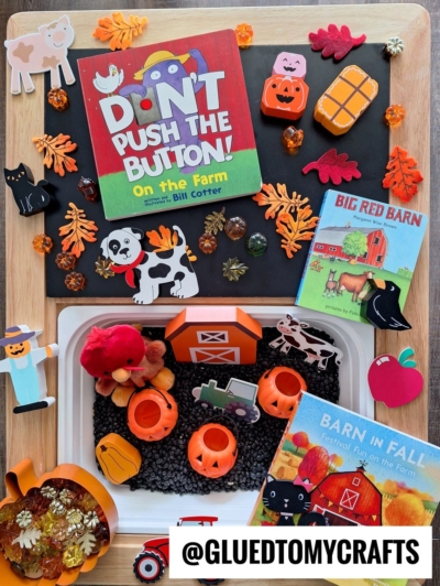 A colorful flat lay of farm-themed children’s books, toy animals, pumpkins, leaves, and Halloween decorations arranged as one of the perfect FALL THEMED SENSORY BIN IDEAS. The handle @GLUEDTOMYCRAFTS appears at the bottom.