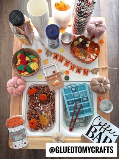 A festive autumn-themed coffee bar setup with pumpkins, leaf cutouts, straws, cups, ice cube tray, mini decorations, and a sign reading “AUTUMN,” perfect for cozy gatherings or as inspiration for fall themed sensory bin ideas.