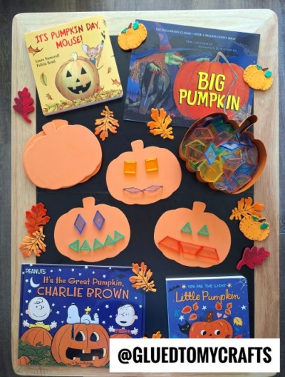 A display of pumpkin-themed children’s books, paper pumpkin crafts with geometric shapes, toy pumpkins, and colorful leaves—plus inspiration for FALL THEMED SENSORY BIN IDEAS—all arranged neatly on a black background. @GLUEDTOMYCRAFTS is written at the bottom.