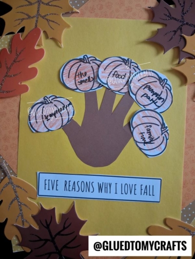 A fall craft featuring a handprint on yellow paper showcases the theme “handprint five reasons.” Each finger, adorned with a pumpkin cutout, lists special reasons to love fall. Surrounded by colorful autumn leaves, the display reads “Five Reasons Why I Love Fall.”.