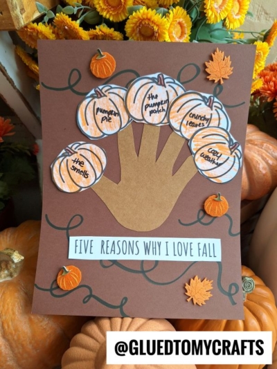 A fall-themed craft features a brown paper handprint on cardstock, surrounded by five reasons to love fall—like pumpkin pie and cool weather—with decorative leaves and pumpkins adding a festive touch.