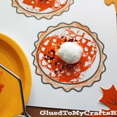 A fall-themed craft features two Potato Masher Stamped Pumpkin Pies with orange paint and cotton ball topping, surrounded by leaf cutouts and fall confetti, plus a paint plate and potato masher nearby.