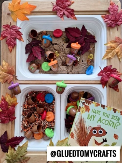 Two FALL THEMED SENSORY BIN IDEAS featuring acorn-shaped containers, colorful tops, artificial leaves, small gems, and textured fillers. The setup includes “Have You Seen My Acorn?” and festive autumn leaves for added fun.
