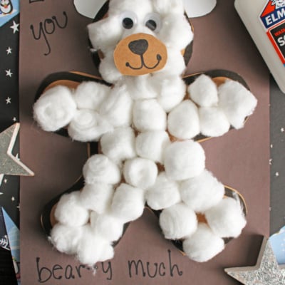 A cotton ball polar bear made of paper is glued to a dark background with handwritten text that says Love you beary much. A bottle of Elmer's glue, paper stars, and FREE PRINTABLE!!! are also visible.