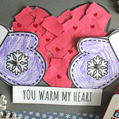 A handmade craft with purple mittens, a red heart crafted from torn paper, and the words You warm my heart. Glue and snowflake decorations surround the craft. Banner at bottom reads Free printable!!!.