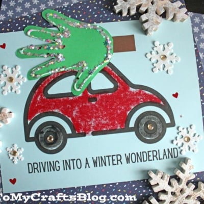 A craft project featuring a red car with a handprint Christmas tree on top, glitter accents, snowflakes, and the text DRIVING INTO A WINTER WONDERLAND.
