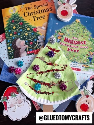 A Christmas-themed craft scene features two children's books about Christmas trees, paper cutouts of Santa and reindeer, and a handmade Paper Plate Christmas Tree decorated with red glitter and mini gift bows.