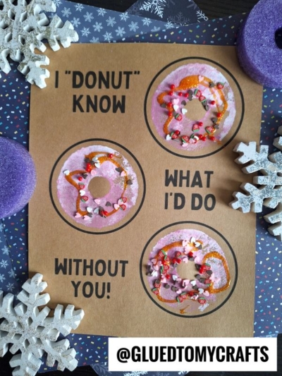 A craft page with three decorated pool noodle stamped donuts. Text reads: I DONUT KNOW WHAT ID DO WITHOUT YOU! The page is surrounded by foam snowflakes and purple foam pieces. @GLUEDTOMYCRAFTS is at the bottom.