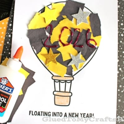 A New Year’s torn paper hot air balloon craft features yellow and black paper, gold glitter stars, and “2026” in red glitter glue. Includes Elmers glue and a "FREE PRINTABLE!!!" for an easy, festive activity.
